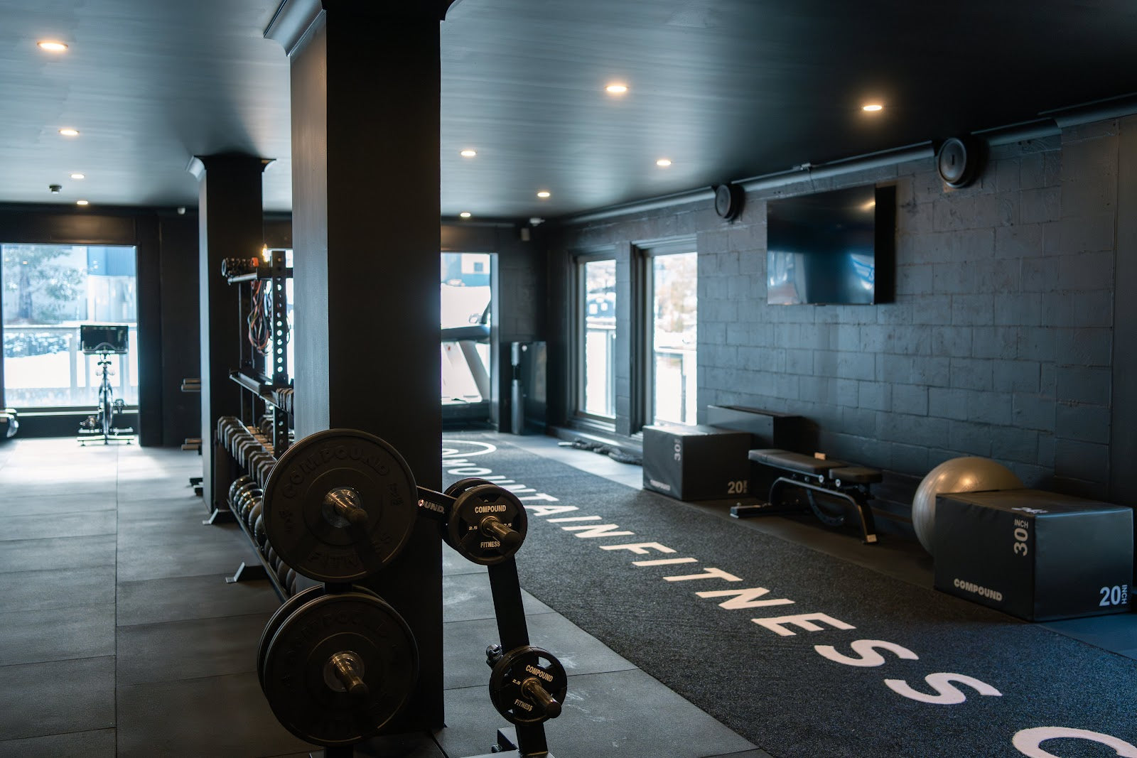 Bright boutique gym floor with windows and branded turf by Compound Fitness