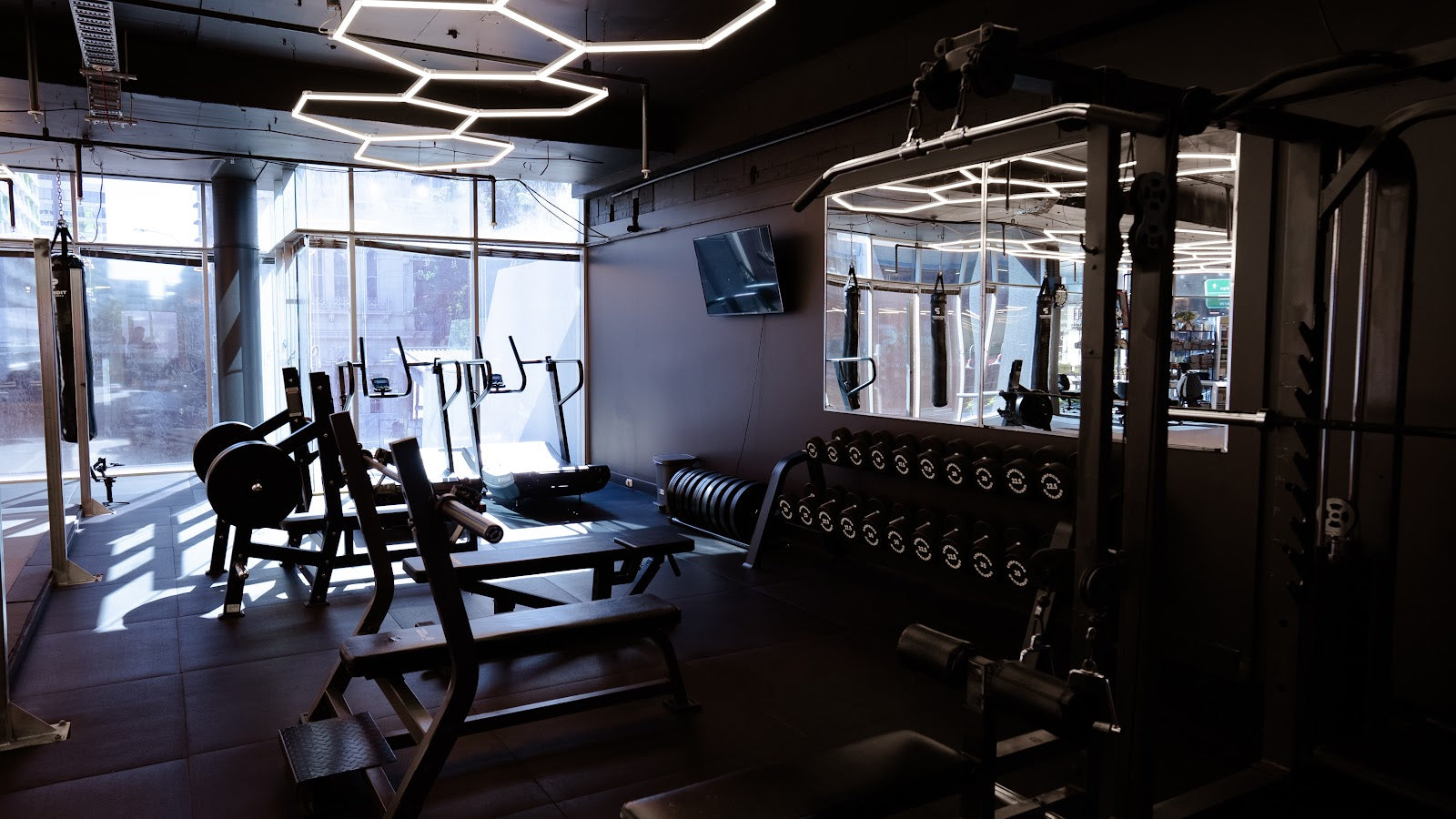 Squat racks and benches by the windows in a boutique studio by Compound Fitness
