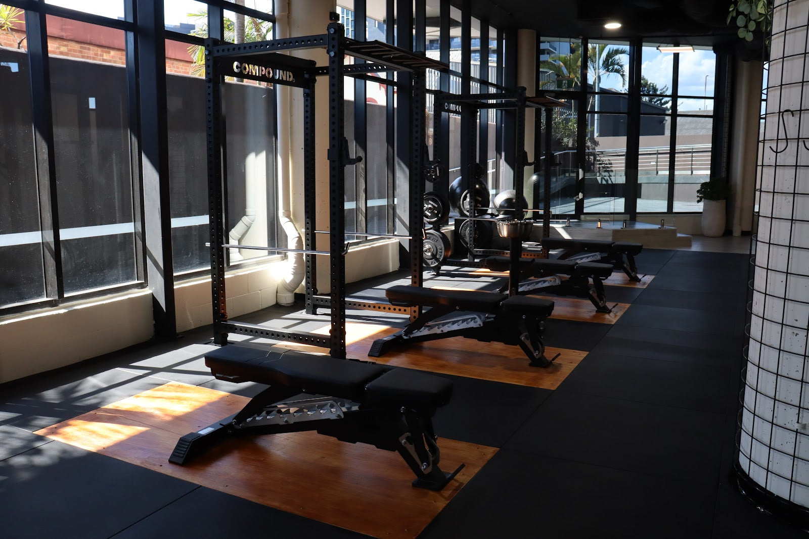 Rack and bench row along a window wall in a boutique gym by Compound Fitness